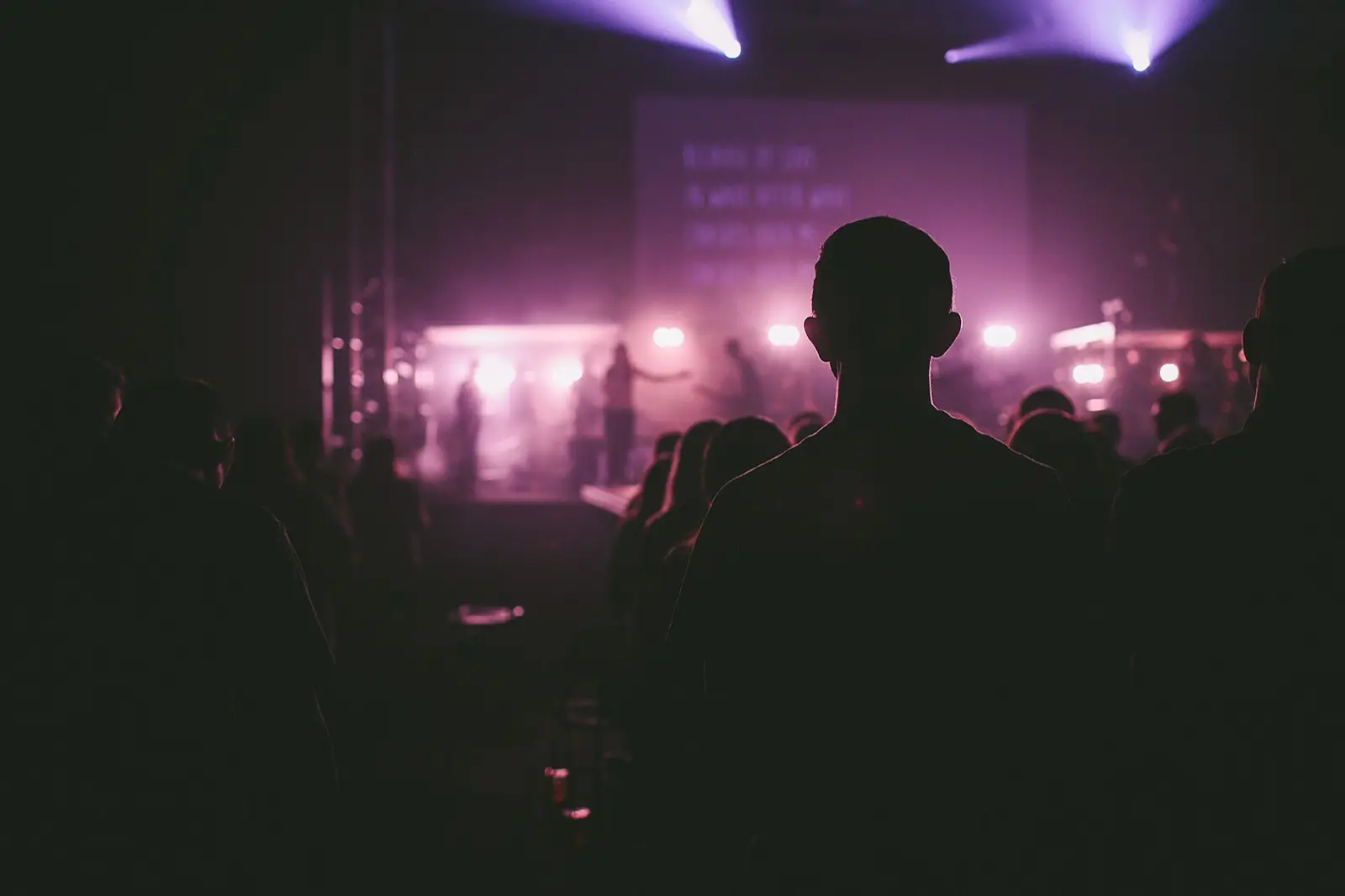A listener in a dark room, facing a softly lit stage