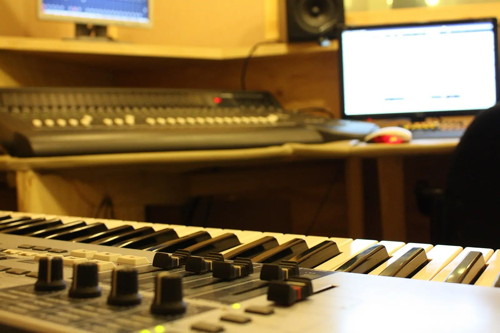 A home studio: a keyboard, a mixing desk and a screen with a session open